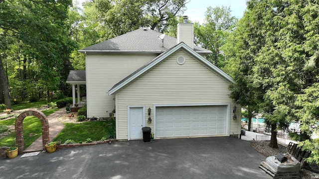 3043 N 400 E Xrd, Monticello, IN 47960 - view of side of property featuring driveway, a chimney, a garage, and a shingled roof