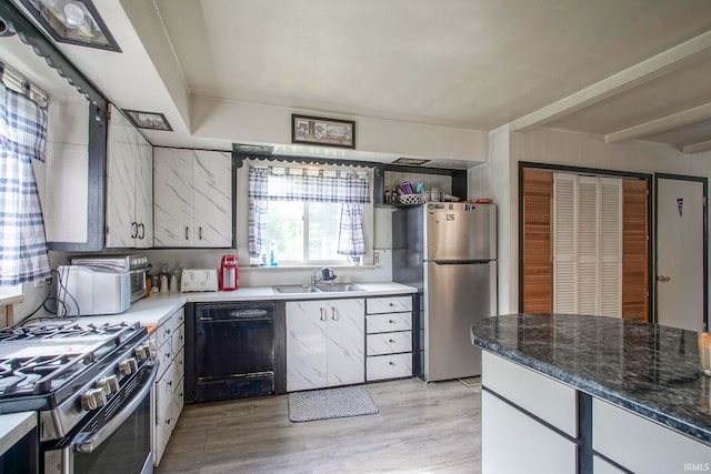 6814 Church St, Lafayette, IN 47905 - kitchen featuring appliances with stainless steel finishes, a sink, light wood-style flooring, white cabinetry, and dark stone countertops