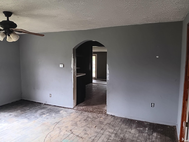 89 Mason St, Bedford, IN 47421 - empty room with arched walkways, a ceiling fan, a textured ceiling, and wood finished floors