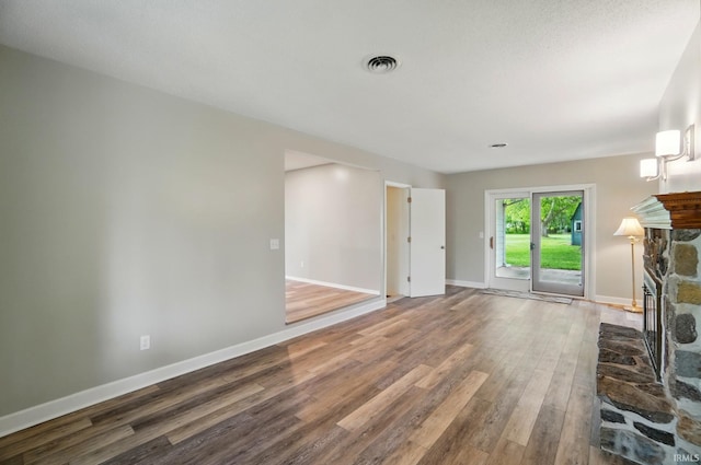 9820 Gerig Rd, Leo, IN 46765 - unfurnished living room with wood finished floors, a stone fireplace, and baseboards