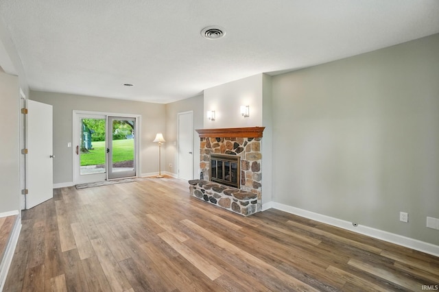 9820 Gerig Rd, Leo, IN 46765 - unfurnished living room with wood finished floors, baseboards, and a stone fireplace