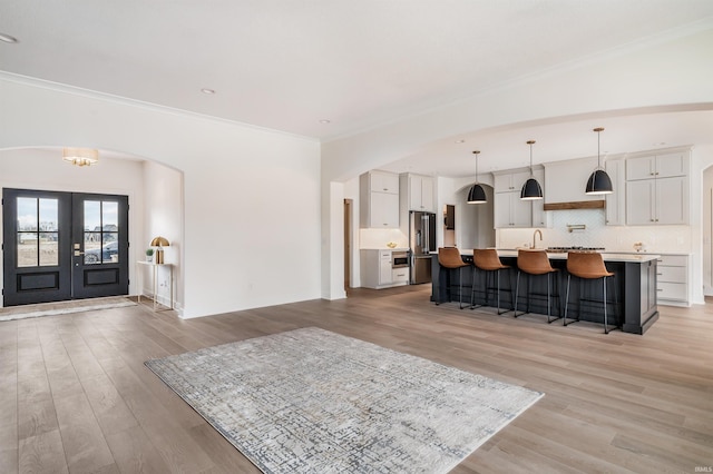 1256 Cascata Trl, Huntertown, IN 46748 - living room with french doors, arched walkways, light wood-style floors, ornamental molding, and baseboards