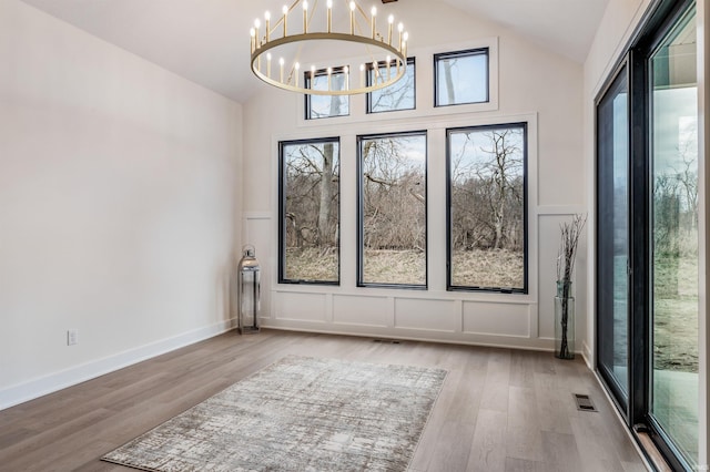 1256 Cascata Trl, Huntertown, IN 46748 - spare room featuring a decorative wall, a chandelier, wood finished floors, high vaulted ceiling, and wainscoting