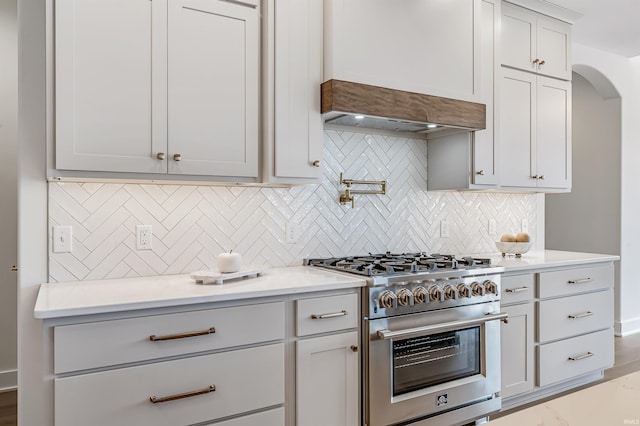1256 Cascata Trl, Huntertown, IN 46748 - kitchen featuring high end range, tasteful backsplash, light countertops, arched walkways, and premium range hood