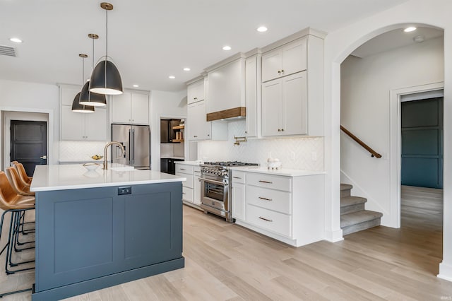 1256 Cascata Trl, Huntertown, IN 46748 - kitchen featuring stainless steel appliances, arched walkways, light countertops, decorative backsplash, and light wood-type flooring