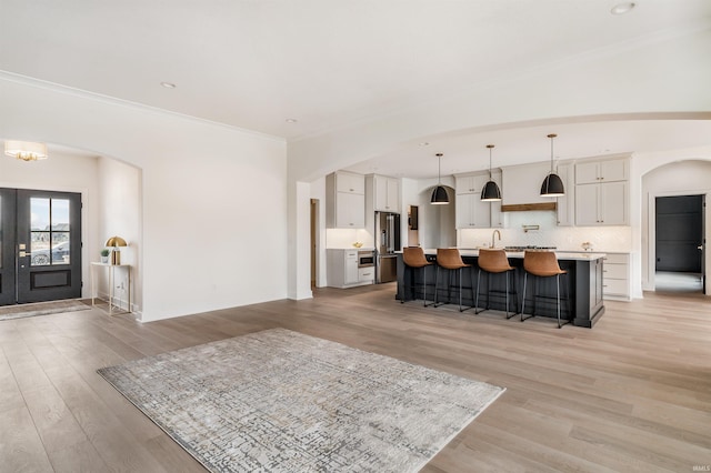 1256 Cascata Trl, Huntertown, IN 46748 - kitchen with arched walkways, high end fridge, a breakfast bar area, light wood finished floors, and crown molding