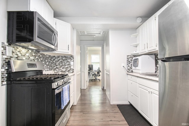 1024 S Lombardy Dr, South Bend, IN 46619 - kitchen featuring stainless steel appliances, light countertops, wood finished floors, white cabinetry, and tasteful backsplash