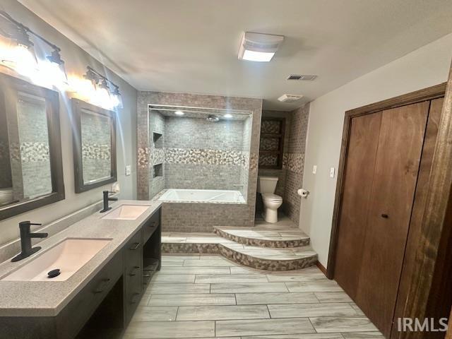 2200 Dakota Dr, Lafayette, IN 47909 - full bathroom featuring tiled bath, toilet, double vanity, and tiled shower