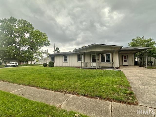 2200 Dakota Dr, Lafayette, IN 47909 - view of front facade featuring board and batten siding, covered porch, an attached carport, a front lawn, and concrete driveway