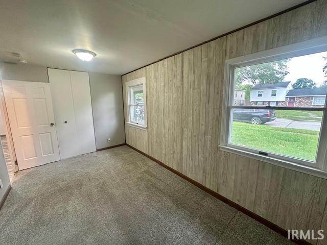 2200 Dakota Dr, Lafayette, IN 47909 - unfurnished bedroom with wood walls, carpet floors, baseboards, and a closet