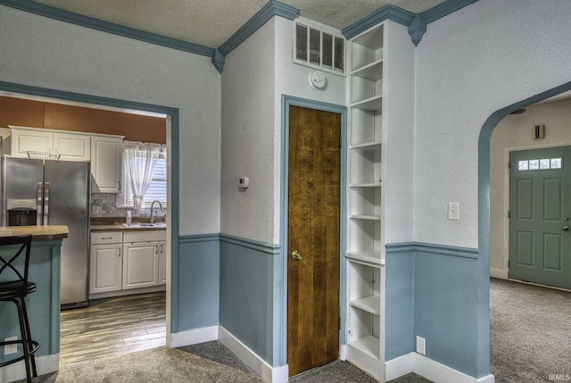 411 E Silver St, Bluffton, IN 46714 - kitchen featuring stainless steel fridge with ice dispenser, a textured wall, a sink, arched walkways, and white cabinets