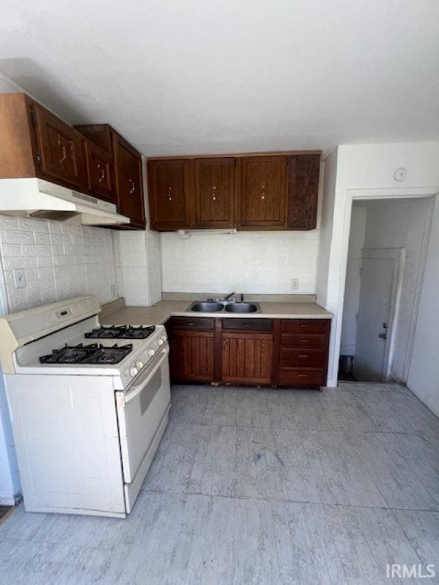 1512 Marine St, South Bend, IN 46613 - kitchen with white gas stove, under cabinet range hood, a sink, and light countertops