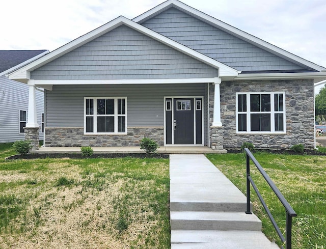 1107 E Wabash St, Frankfort, IN 46041 - craftsman-style home with stone siding, a porch, and a front lawn