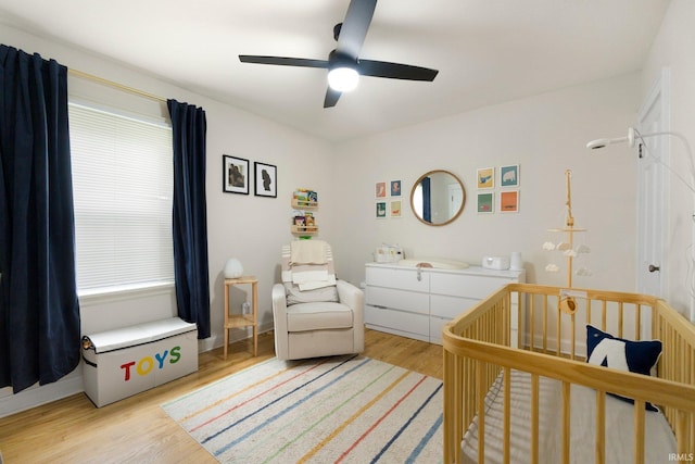 1324 Maple Ave, Fort Wayne, IN 46807 - bedroom featuring light wood-style floors, a crib, ceiling fan, and baseboards