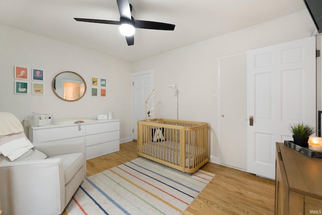 1324 Maple Ave, Fort Wayne, IN 46807 - bedroom featuring light wood-type flooring, a crib, a ceiling fan, and baseboards