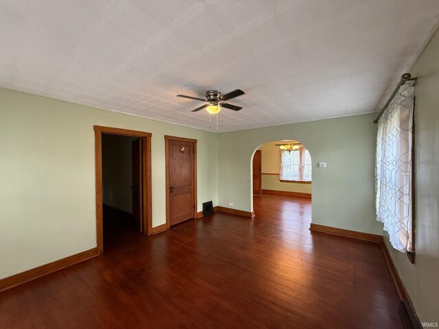 502 Keller St, North Judson, IN 46366 - spare room with arched walkways, dark wood-type flooring, ceiling fan, and baseboards