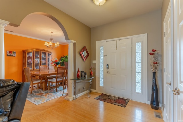 9142 Hartwell Dr, Evansville, IN 47725 - foyer featuring decorative columns, light wood-type flooring, arched walkways, a chandelier, and healthy amount of natural light