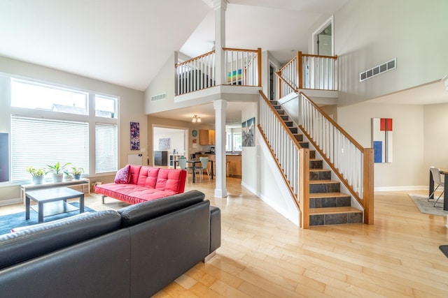 3513 Crater Cv, Fort Wayne, IN 46804 - living area with decorative columns, high vaulted ceiling, stairs, light wood-style floors, and healthy amount of natural light