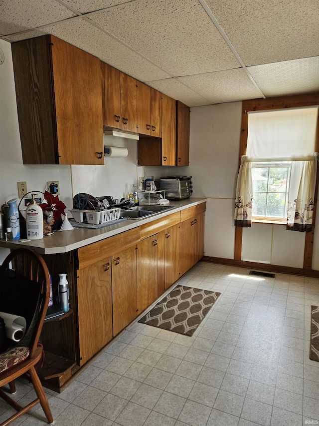 115 High St, Geneva, IN 46740 - kitchen with a paneled ceiling, light countertops, brown cabinets, light floors, and baseboards