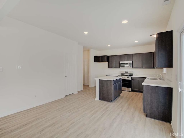 1006 E Brandy Blvd, Ellettsville, IN 47429 - kitchen with appliances with stainless steel finishes, a sink, light wood-style floors, a center island, and light countertops