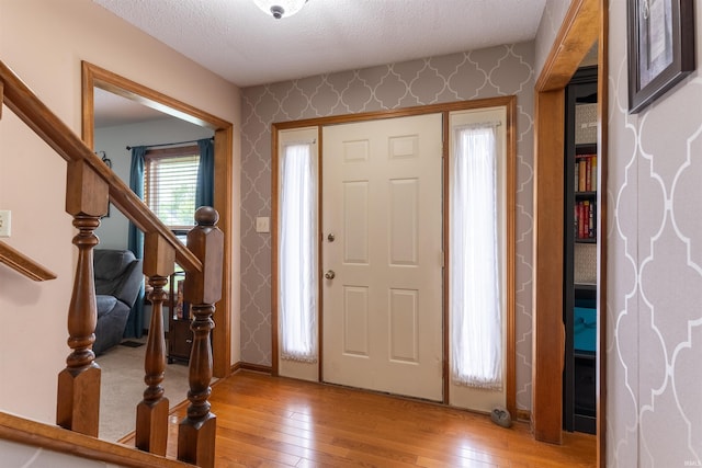 620 Bob Ct, Evansville, IN 47711 - entryway with wallpapered walls, light wood-style floors, a textured ceiling, and stairway