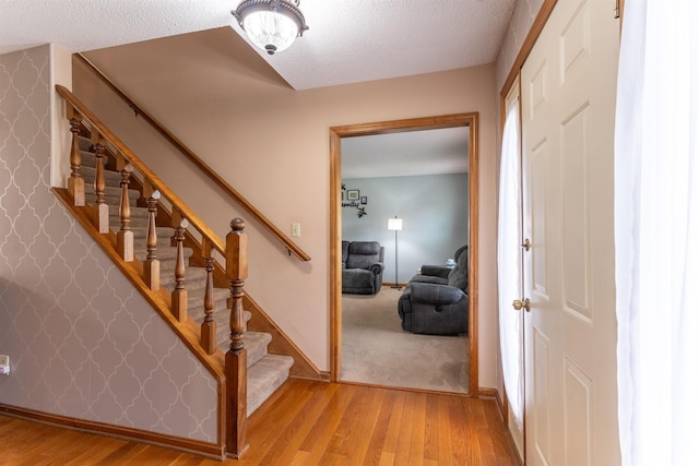 620 Bob Ct, Evansville, IN 47711 - stairs featuring wood finished floors, a textured ceiling, and baseboards