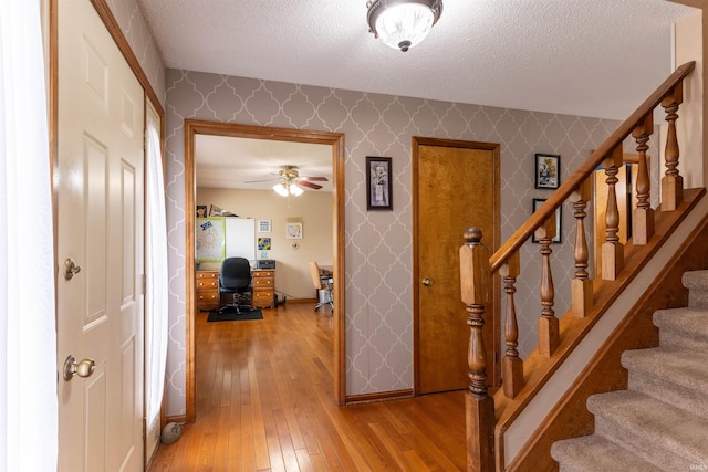 620 Bob Ct, Evansville, IN 47711 - stairway featuring wallpapered walls, hardwood / wood-style floors, a textured ceiling, and ceiling fan