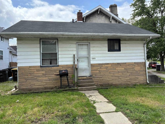 2901 Broadway, Fort Wayne, IN 46807 - view of front facade featuring entry steps, stone siding, a chimney, a front yard, and roof with shingles