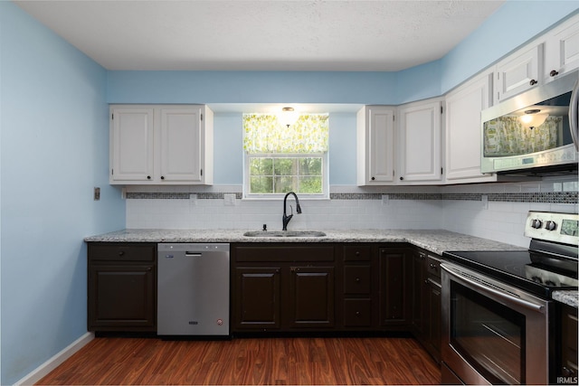 1804 Bent Tree Trl, West Lafayette, IN 47906 - kitchen featuring appliances with stainless steel finishes, a sink, white cabinets, dark wood-type flooring, and decorative backsplash
