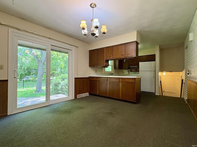 141 Indian Rock Dr, West Lafayette, IN 47906 - kitchen with freestanding refrigerator, a chandelier, dark colored carpet, light countertops, and a wainscoted wall