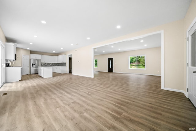 2416 S Woodland Trl, Warsaw, IN 46580 - unfurnished living room featuring light wood-style flooring, recessed lighting, baseboards, and a sink