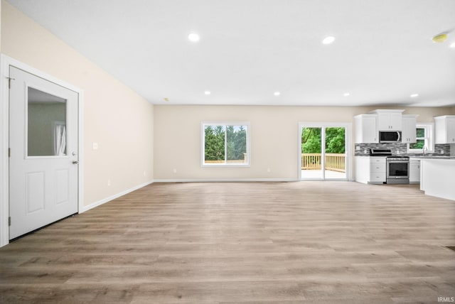 2416 S Woodland Trl, Warsaw, IN 46580 - unfurnished living room featuring light wood-style flooring, recessed lighting, baseboards, and a sink