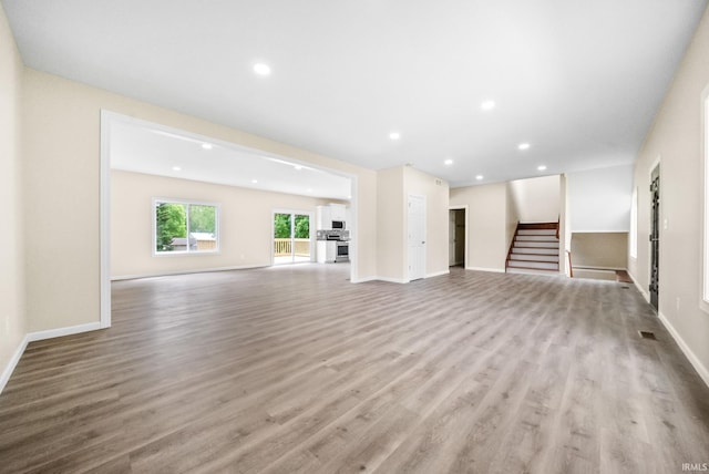 2416 S Woodland Trl, Warsaw, IN 46580 - unfurnished living room featuring wood finished floors, stairs, baseboards, and recessed lighting