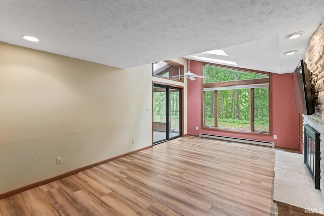 2730 Newman Rd, West Lafayette, IN 47906 - unfurnished living room with baseboard heating, a fireplace, a textured ceiling, light wood-style floors, and baseboards