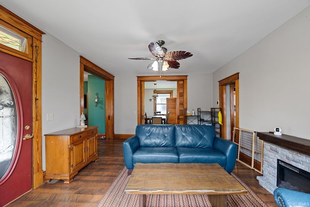 1824 Maple St, Lafayette, IN 47904 - living room featuring a ceiling fan, dark wood-style flooring, a stone fireplace, and baseboards