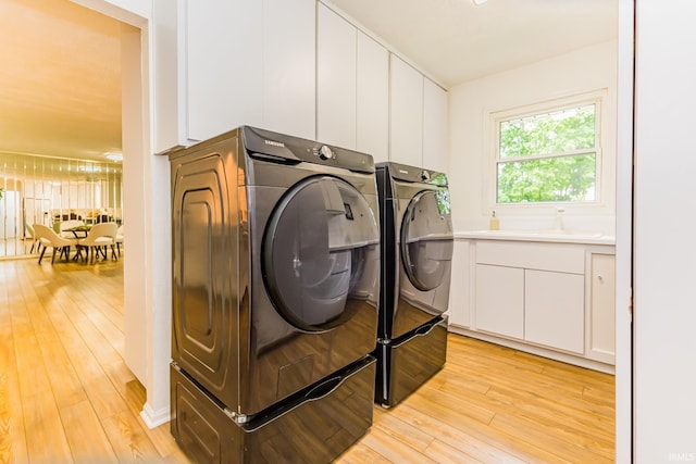 6607 W Ryan Dr, Anderson, IN 46011 - laundry area featuring separate washer and dryer, light wood-style floors, and cabinet space