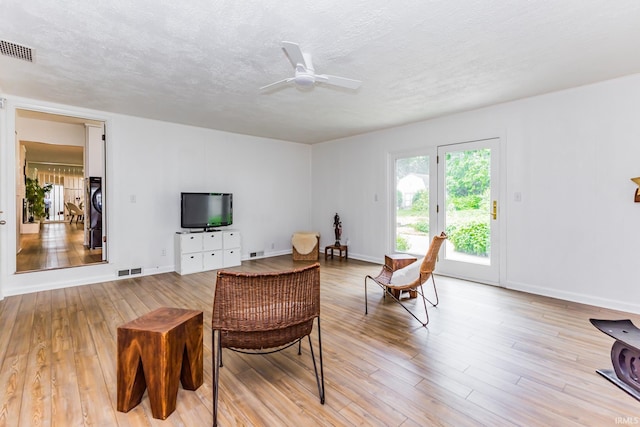 6607 W Ryan Dr, Anderson, IN 46011 - living room with light wood-style floors, ceiling fan, baseboards, and a textured ceiling