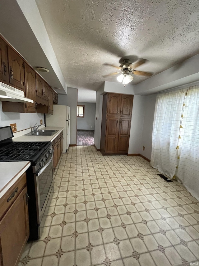 2724 Elva Dr, Kokomo, IN 46902 - kitchen featuring stainless steel range with gas cooktop, under cabinet range hood, light flooring, light countertops, and ceiling fan