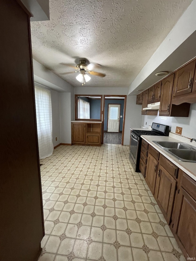2724 Elva Dr, Kokomo, IN 46902 - kitchen with stainless steel gas stove, under cabinet range hood, a sink, light countertops, and light flooring
