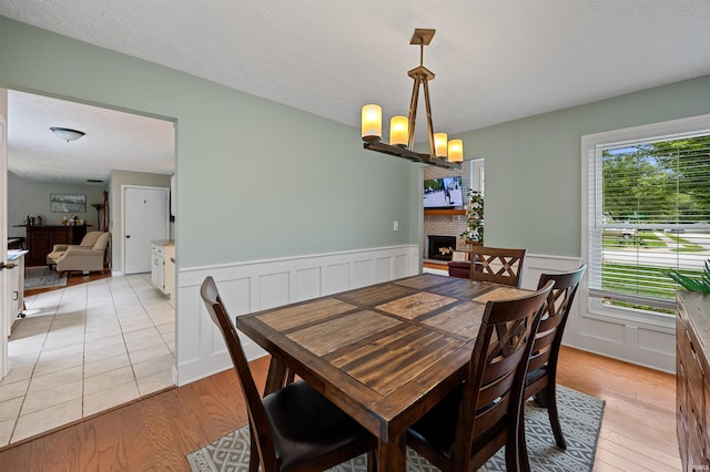 2218 Wake Robin Dr, West Lafayette, IN 47906 - dining area featuring a wainscoted wall, light wood finished floors, a chandelier, a decorative wall, and a fireplace