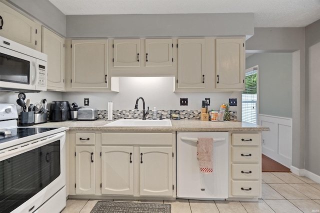 2218 Wake Robin Dr, West Lafayette, IN 47906 - kitchen with white appliances, a sink, light countertops, light tile patterned floors, and wainscoting