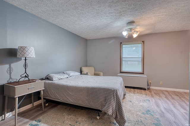 907 Nicholas Dr, Boonville, IN 47601 - bedroom with light wood-style floors, a textured ceiling, baseboards, and radiator