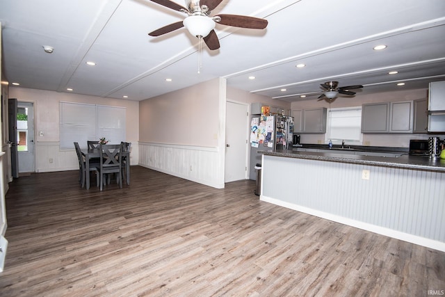 1416 State St, Vincennes, IN 47591 - kitchen featuring dark countertops, a ceiling fan, a wainscoted wall, wood finished floors, and a sink