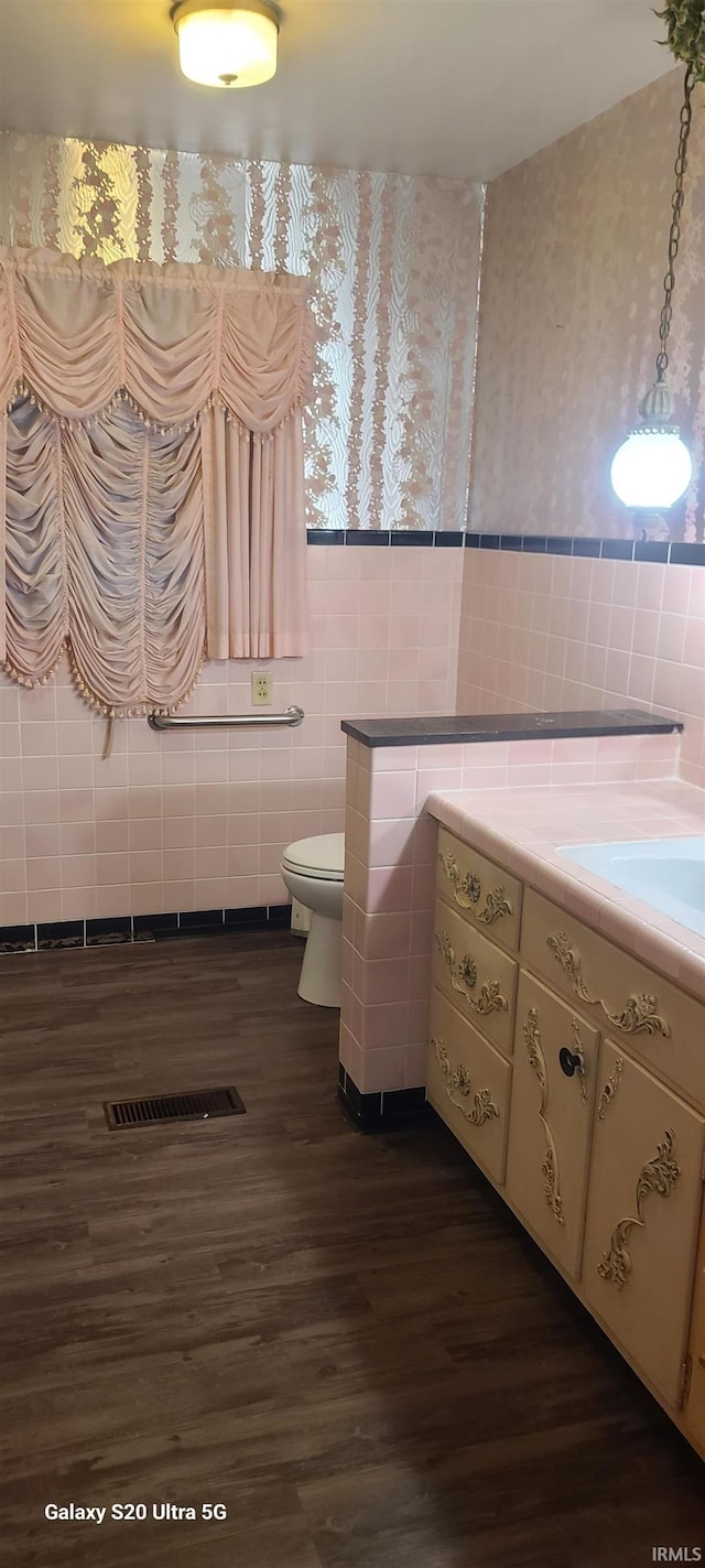 1202 N Sheridan Rd, Marion, IN 46952 - bathroom featuring vanity, tile walls, wood finished floors, toilet, and wallpapered walls