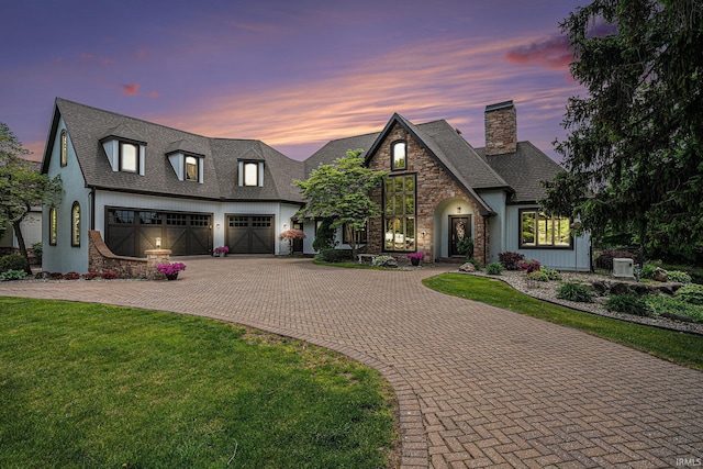 20870 N River Ridge Drive, Bristol, IN 46507 - french country inspired facade featuring decorative driveway, a chimney, stone siding, an attached garage, and a yard