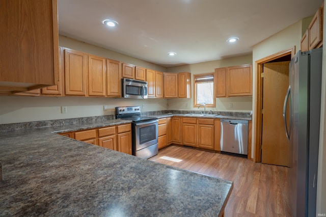 7768 S 100 W, North Judson, IN 46366 - kitchen with stainless steel appliances, a sink, light wood-style flooring, dark countertops, and recessed lighting