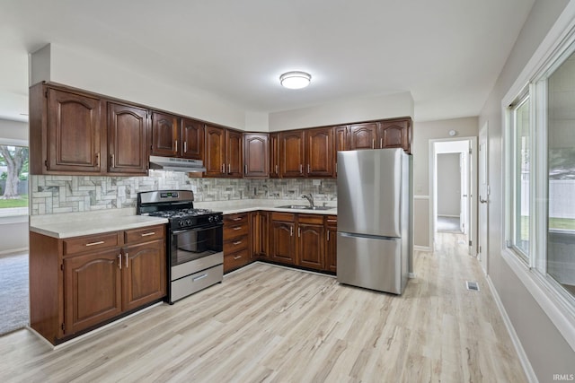 1813 Crescent Dr, Warsaw, IN 46580 - kitchen with stainless steel appliances, under cabinet range hood, light wood finished floors, light countertops, and backsplash