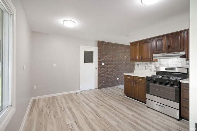 1813 Crescent Dr, Warsaw, IN 46580 - kitchen with gas range, under cabinet range hood, light countertops, light wood finished floors, and decorative backsplash