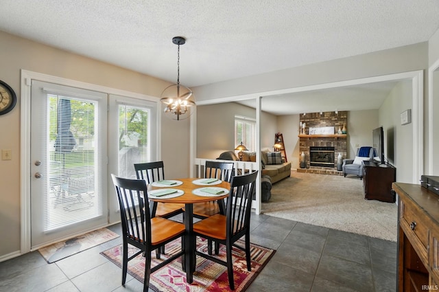 8427 Victoria Woods Pl, Fort Wayne, IN 46825 - dining space with a chandelier, a fireplace, dark tile patterned floors, dark colored carpet, and a textured ceiling