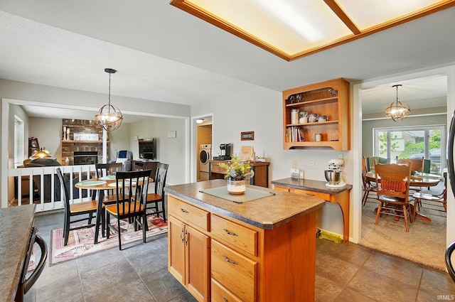 8427 Victoria Woods Pl, Fort Wayne, IN 46825 - kitchen with a chandelier, a fireplace, dark countertops, a center island, and decorative light fixtures